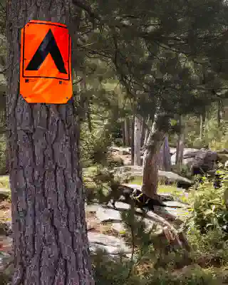 An Orange sign shows the image of a tent. Typical sign for a campsite.