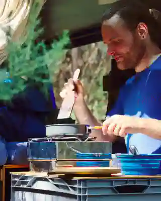 Georg brät in einer kleinen Pfanne Pancakes. Die Pfanne steht auf unserem Spirituskocher.