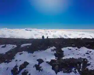 Ein Berggipfel mit schnee und Eis. Strahlen blauer himmel und die Wolken im Hintergrund. 