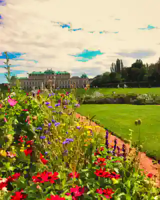 Many flowers in a manicured flower bed. In the backround, a withe castle-like building