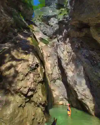 A waterfall with a pool. Jo is standing in it.