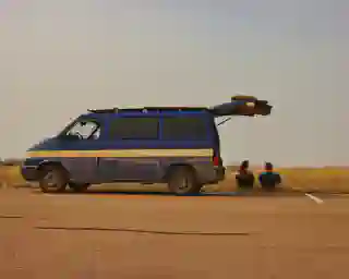 Seitenansicht auf unseren Bus, die Heckklappe steht offen. Wir sitzen mit unseren Stühlen unter der Heckklappe und genießen die Aussicht