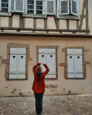 Jo in ihrem roten Regenmantel vor einem Fachwerkhaus in Colmar