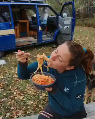 Jo is eating spaghetti Bolognese. In the background, the van is visible