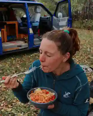 Jo is eating spaghetti Bolognese. In the background, the van is visible.