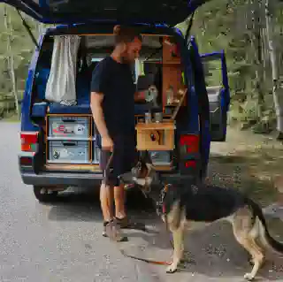 Georg steht an unserer Küchenbox und kocht Kaffee. Vor ihm sitzt Momo und schaut ihm zu