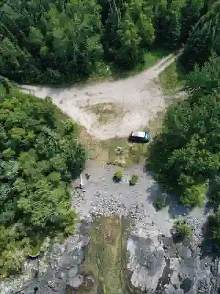 Aerial view of the campsite at Lake Superior. The Quest is positioned on a small rocky beach surrounded by trees. 