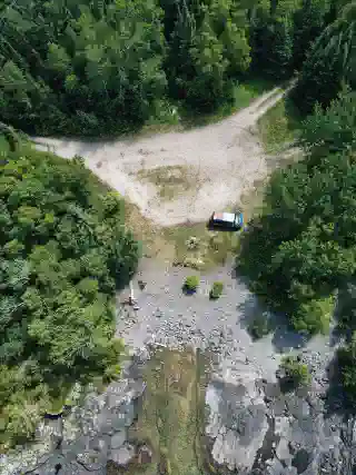 Luftbildafnahme vom Stellplatz am Lake Superior. Die Quest steht an einem kleinen Steinstrand umrundet von Bäumen. 