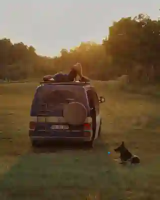 Sunset in Saskatchewan, campsite on a green field surrounded by trees. Georg is lying on the rooftop terrace, enjoying the rays of the sun.