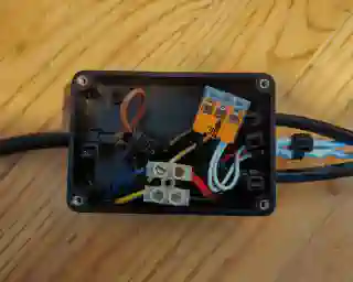 Inside the junction box. On the left, cables from the submersible pump, tank sensor, and LEDs go in; on the right, a 4-core cable comes out.